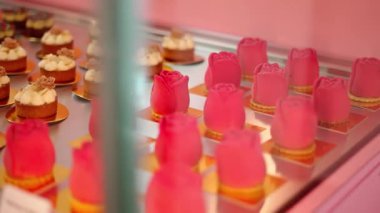 Altın tepsilerdeki kadife pembe kremalı zarif gül şekilli tatlılar, şekerleme kabında sunuluyor..