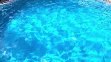 Güneşli bir günde yüzme havuzunun mavi yüzeyi.