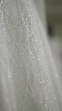 Kısa ömürlü bir gelinlikteki boncukların ışıltısı, narin cazibesini vurguluyor..