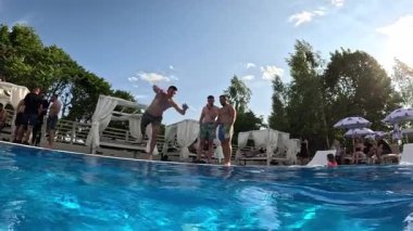 Güneşli bir günde yüzme havuzunda ters takla atan bir adam. Yaz eğlencesi..