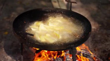 Kızartma tavasında yağda kızartılmış patates parçaları açık ateşte kızartılır..