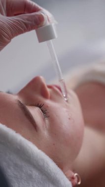 Kozmetik serumu, bir güzellik kliniğinde bir kadının yüzüne yakın çekim bir cilt bakımı yöntemi kullanarak uygulanır..