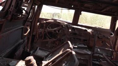 İçi yanmış, harap olmuş bir araba, terk edilmiş, savaş zamanı yıkımının ve trajedinin sembolü..