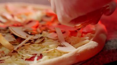 Pişirme işleminden önce taze pizzaya peynirli ve mantarlı dilimlenmiş malzemeler eklemek..