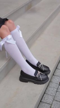 Zarif fiyonklu bir kız için siyah ayakkabılar beyaz golf ayakkabıları, çocuk modasının modern detayları, şık ve şık ayakkabılar..