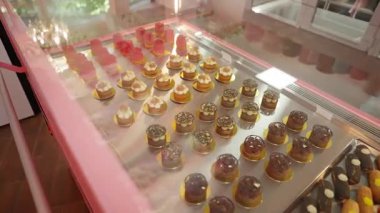 Çeşitli gurme mini kekler ve eklerlerle hamur işi vitrininde, renkli tatlı ikramları tepsilerde sunulan lüks pastanenin içinde..