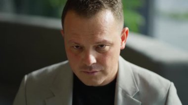 The camera focuses on the businessmans face, emphasizing his seriousness and thoughtful expression.