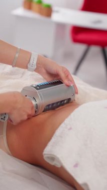 Professional body contouring procedure, specialist uses modern vacuum therapy equipment to tone skin and reduce cellulite in spa salon.