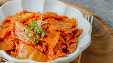 Yağla yağlanmış tavada doğranmış yeşil soğan ve sarımsaklı mayalanmış kimchi, genellikle pirinçle yenen popüler bir mezedir. Soya peyniri ile de iyi gider..