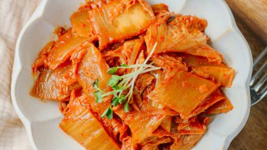 Yağla yağlanmış tavada doğranmış yeşil soğan ve sarımsaklı mayalanmış kimchi, genellikle pirinçle yenen popüler bir mezedir. Soya peyniri ile de iyi gider..