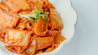 Yağla yağlanmış tavada doğranmış yeşil soğan ve sarımsaklı mayalanmış kimchi, genellikle pirinçle yenen popüler bir mezedir. Soya peyniri ile de iyi gider..