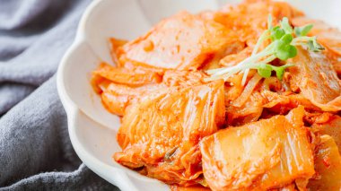 Yağla yağlanmış tavada doğranmış yeşil soğan ve sarımsaklı mayalanmış kimchi, genellikle pirinçle yenen popüler bir mezedir. Soya peyniri ile de iyi gider..