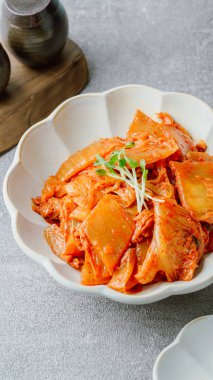 Yağla yağlanmış tavada doğranmış yeşil soğan ve sarımsaklı mayalanmış kimchi, genellikle pirinçle yenen popüler bir mezedir. Soya peyniri ile de iyi gider..