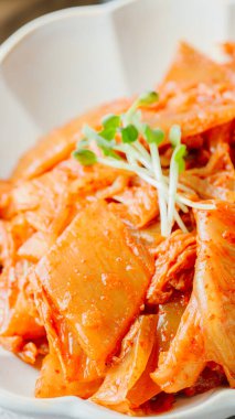 Yağla yağlanmış tavada doğranmış yeşil soğan ve sarımsaklı mayalanmış kimchi, genellikle pirinçle yenen popüler bir mezedir. Soya peyniri ile de iyi gider..