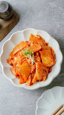 Yağla yağlanmış tavada doğranmış yeşil soğan ve sarımsaklı mayalanmış kimchi, genellikle pirinçle yenen popüler bir mezedir. Soya peyniri ile de iyi gider..