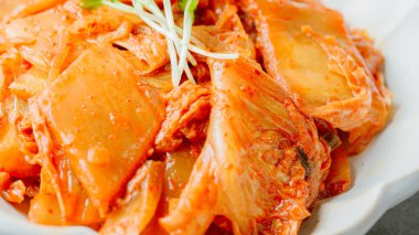 Yağla yağlanmış tavada doğranmış yeşil soğan ve sarımsaklı mayalanmış kimchi, genellikle pirinçle yenen popüler bir mezedir. Soya peyniri ile de iyi gider..