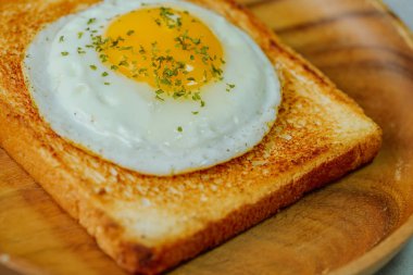 Tahta tabakta kızarmış yumurta ve kızarmış ekmek.