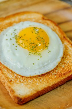 Tahta tabakta kızarmış yumurta ve kızarmış ekmek.