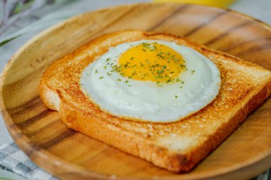 Tahta tabakta kızarmış yumurta ve kızarmış ekmek.