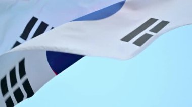Güney Kore bayrağının yakın çekimi, Taegukgi, açık bir yaz gökyüzüne karşı rüzgarda dalgalanıyor..