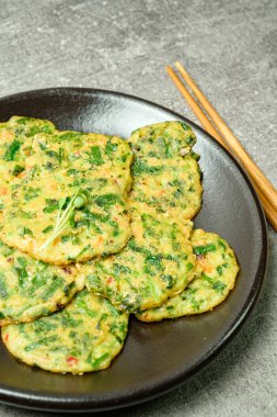 Buchujeon, Kore Chive Pancake 'i bu yemeği hazırlamak için jülyen, havuç ve yeşil biber unla karıştırılır ve tavada krep şeklinde düz, yuvarlak bir şekilde kızartılır.