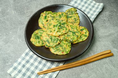 Buchujeon, Kore Chive Pancake 'i bu yemeği hazırlamak için, soğan, jülyen havuç ve yeşil biber unla karıştırılır ve tavada kızartılır, yuvarlak, krep şeklinde. Krep daha sonra sirke bazlı soya sosuyla servis edilir..