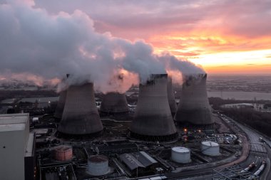 Kirli kömür santralinin hava manzarası soğutma kuleleri gün batımında atmosferi karbondioksit emisyonlarıyla kirletiyor.