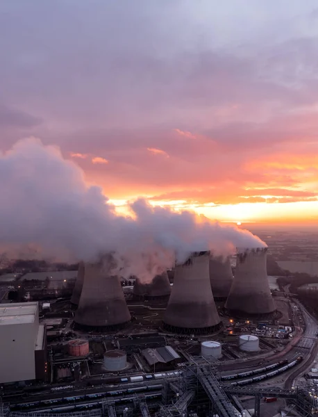 Aerial view of dirty coal fired power station cooling towers polluting the atmosphere with carbon dioxide emissions at sunset