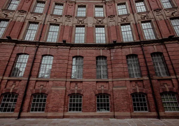Full frame wide angle view of an imposing Victorian factory building with red brick and rows of ornate window frames and architrave with copy space