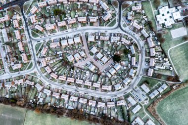 Aerial view directly above the snow covered streets and rooftops of a suburban residential development  with cul de sac road system