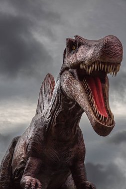 A ferocious Dinosaur named Spinosaurus with mouth wide open and showing its razor sharp teeth against a dramatic sky with copy space