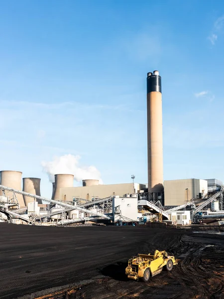 A heavy plant machine scraping coal from a fossil fuel stack at a large coal fired power station to burn for non-renewable electricity generation