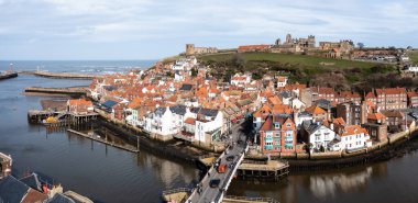Whitby, İngiltere - 12 Mart 2023. Whitby Abbey ile birlikte Kuzey Yorkshire 'da Whitby limanının ve sahil kasabasının havadan manzarası