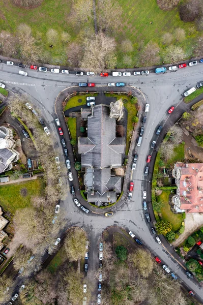 Aerial view directly above a church at the heart of a local community with cars parked outside as people arrive to worship