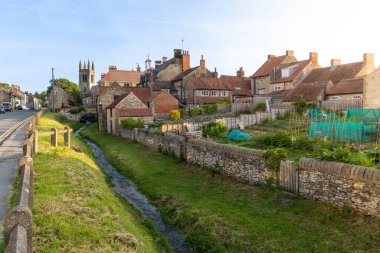 Local allotments nestled amongst the old fashioned buildings and stream in the popular tourist destination of Helmsley in Yorkshire clipart