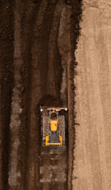 Doğrudan buldozer ya da toprak hareket makinesinin üzerinde inşaat endüstrisindeki toprak ve toprağı fotokopi alanı olan bir kahverengi alan sahasında iten raylar var.