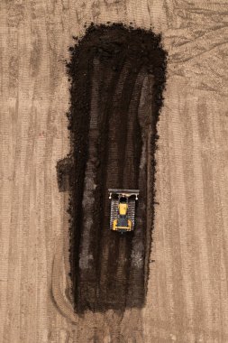 Doğrudan buldozer ya da toprak hareket makinesinin üzerinde inşaat endüstrisindeki toprak ve toprağı fotokopi alanı olan bir kahverengi alan sahasında iten raylar var.