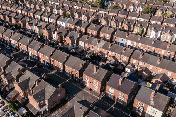 An aerial view above the drab rooftops of run down back to back terraced houses on a large residential estate in the North of England
