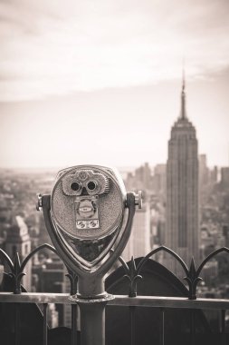 Eski moda madeni para Empire State binasına bakan dürbünler kullanıyordu ve Manhattan 'ın göbeğindeki semti klasik bir fotoğraf tarzıyla Top of the Rock' tan çevreledi.