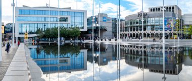 CENENENENENENARY Squarare, BIRMINGHAM, İngiltere - 5 Ekim 2023. Birmingham 'ın yeni Senfoni Salonu ve Rep tiyatrosunun panoramik manzarası şehir merkezindeki Centenary Meydanı' ndaki çeşmeye yansıdı.