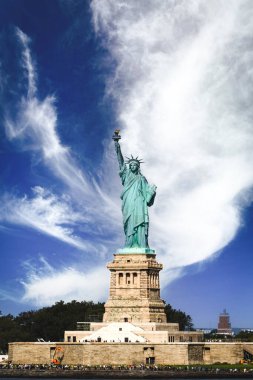 LIBERTY, New York, ABD - 16 EYLÜL 2023. Beyaz bulutlar ve mavi gökyüzü ile güneşli bir günde turistlerle dolu Özgürlük ve Özgürlük Heykeli 'nin kara manzarası.