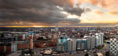 Gündoğumunda modern apartman binaları dramatik gökyüzü olan Batı Yorkshire 'daki Leeds şehir siluetinin panoramik bir görüntüsü.