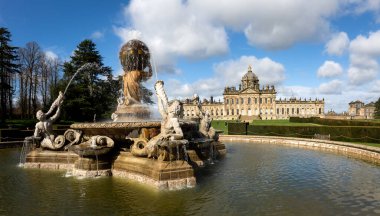 CASTLE HOWARD, YORK, UK - 23 Mart 2024. Howardian Hills 'teki Howard Stately House Kalesi' nin resmi bahçelerindeki Atlas Çeşmesi manzarası. Güneş ışığı ve mavi gökyüzü.