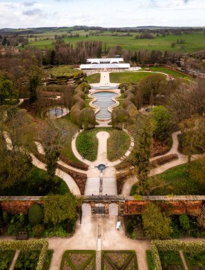 ALNWICK GARDENS, NORTHUMBERLAND, UK - APRIL 19, 2024.  Aerial vertorama landscape view of the formal gardens at Alnwick Castle with The pavilion building clipart