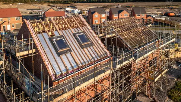 stock image Aerial view of a roof under construction with beams and apex supporting exterior skylight windows on a new build house surrounded by scaffolding on a construction site