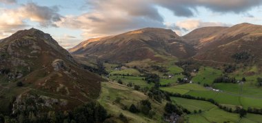 Helm Crag ve Helvellyn dağlarının gündoğumunda A591 Grasmere 'den Keswick yoluna uzanan ve vadiden Thirlmere Gölü' ne giden İngiliz Lake District Ulusal Parkı 'ndaki panoramik manzarası.
