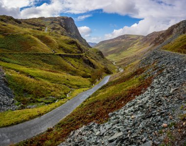 A landscape view of the top of the  B5289 Honister Pass road from The Honister Slate Mine in The English Lake District National Park on a sunny Summer day clipart