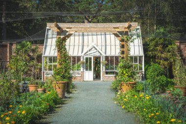 İngiliz kır bahçesinde Victoria tarzı serası ve sebze bahçesi olan güzel bir resmi bahçe.