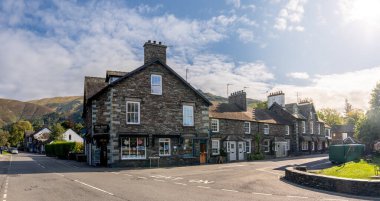 GRASMERE, CUMBRIA, UK - SEPTEMBER 13, 2024.  Panoramic landscape of shops including Sam Reed book shop in the centre of Grasmere village in the English Lake District National Park clipart