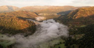 Aerial panoramic landscape of low lying mist or cloud inversion over Grasmere and Rydal Water lakes in  the Lake District National Park on a cold Autumn morning with sunrise clipart